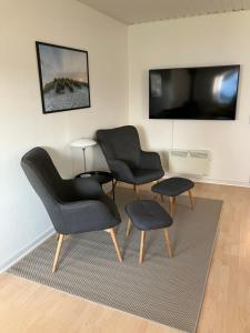 a living room with two chairs and a tv at Lejlighed i naturskønt område in Bratten Strand