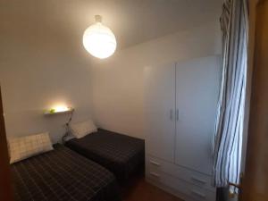 a small bedroom with a bed and a light at apartamento Atlanta in Chipiona