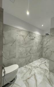 a bathroom with a white toilet and marble walls at The White Troy in Sarandë +80 photos