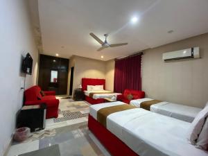 a room with three beds and a couch and a ceiling at Hotel Tulip Inn, Gulberg in Lahore