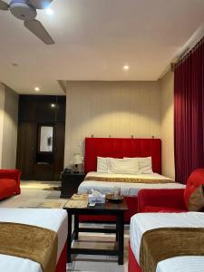 a hotel room with two beds and a red headboard at Hotel Tulip Inn, Gulberg in Lahore