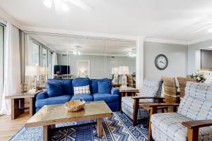 Una sala de estar con un sofá azul y una mesa. en Waters Edge 105, en Fort Walton Beach