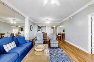 Una sala de estar con un sofá azul y una mesa. en Waters Edge 105, en Fort Walton Beach