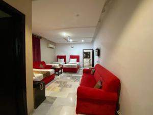 a living room with red chairs and a red couch at Hotel Tulip Inn, Gulberg in Lahore