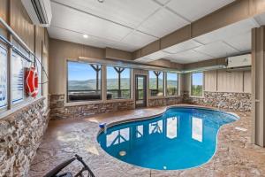 a large swimming pool in a room with a stone wall at Breathtaking View Mountain Lux Games Pool Theater in Cove Creek Cascades