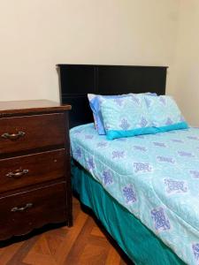a bed with a blue comforter and a wooden dresser at Hermosa habitación en el corazón de Otavalo in Otavalo