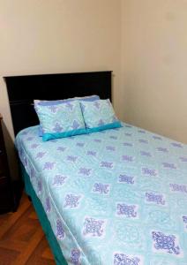a bed with a blue and white quilt and two pillows at Hermosa habitación en el corazón de Otavalo in Otavalo +7 photos
