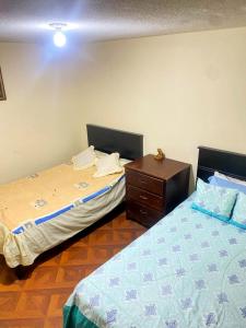 a bedroom with two beds and a wooden dresser at Hermosa habitación en el corazón de Otavalo in Otavalo