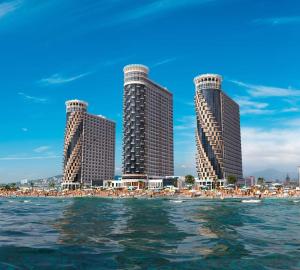 three tall buildings on a beach with umbrellas at Apartment Rimma in Batumi