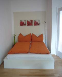 メードリングにあるApartment Mödlingの白い部屋のベッド(オレンジの枕付)