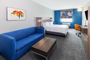a hotel room with a blue couch and a bed at Holiday Inn Express Harvey-Marrero by IHG in Harvey