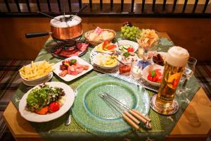 a table with plates of food and a beer at Hotel Landhaus Carla in Mayrhofen