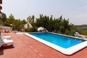 a swimming pool on a brick patio with a white chair at Finca El Escondite in Olocau