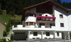 a white house with a balcony with pink flowers on it at Apart La Stella in Kappl