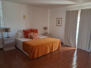 a bedroom with a bed with an orange blanket at Dona Ana Guesthouse in Lagos