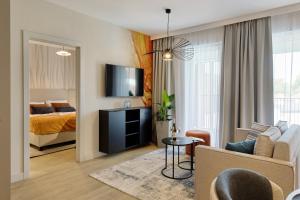 a living room with a couch and a bed and a tv at Resort Baltic Waves Apartments - Basen, Sauna in Międzyzdroje