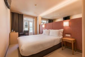 a hotel room with a large bed and a chair at Hotel Margarida Da Praça in Viana do Castelo