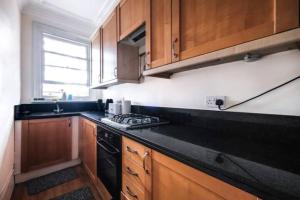 a kitchen with wooden cabinets and a black counter top at Harrods-Knightsbridge Flat in Central KB89 in London +11 photos