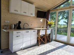a kitchen with white cabinets and a large window at Dolina Baryczy 5 Kotów in Żmigród