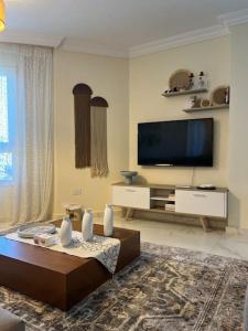 a living room with a flat screen tv and a couch at Charming apartment In Heliopolis in Cairo