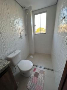 a white bathroom with a toilet and a window at Zaffir Apartamento in Cuiabá +9 photos