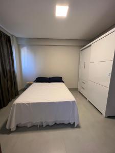 a bedroom with a white bed and a cabinet at Zaffir Apartamento in Cuiabá
