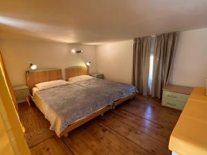 a bedroom with a large bed and wooden floors at Casetta Jema in Lumio