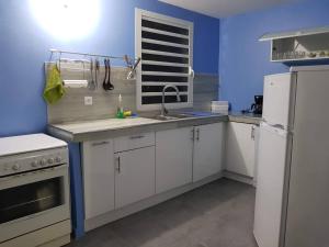 a kitchen with white cabinets and a blue wall at Green Garden in Roussel