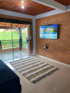 un salon avec une télévision sur un mur en briques dans l'établissement Casa do Rafael, à Conceição da Ibitipoca