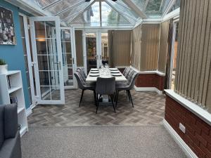 a glass conservatory with a table and chairs on a patio at Huge 9 Bed Property Sleeps 17, Near NEC, City Centre, HS2 in Birmingham