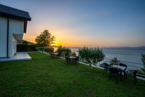 a group of tables and chairs on a lawn with the sunset at Xhuli Guesthouse in Shirokë