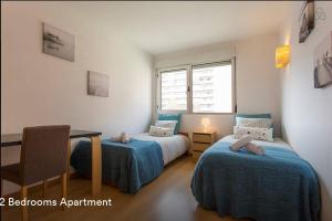 a bedroom with two beds and a desk and a window at Cardoso Pires 2 Bedrooms Apt. in Lisbon