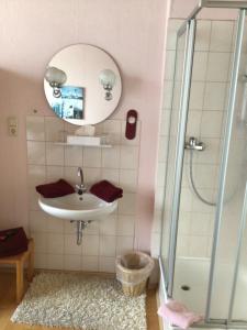 a bathroom with a sink and a shower at Pension „La Rose“ in Norden