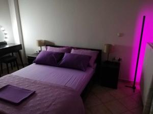 a bedroom with a purple bed with a pink light at NK Dreamy Suite in Thiva