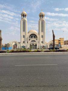 a large white building with two towers on a street at Studio near airport in Cairo