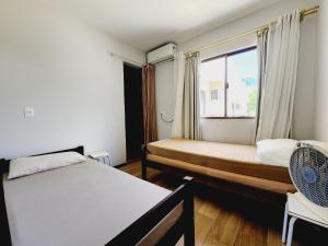 a bedroom with two beds and a window at Sobrado 30 m praia, quartos climatizados, 1 vaga, até 6 pessoas in Bombinhas