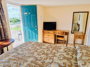 a bedroom with a bed and a desk and a television at Anne Shirley Motel & Cottages in Cavendish