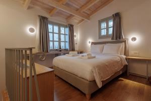a bedroom with a large bed and two windows at Eligia Suites in Ioannina