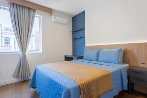 una camera da letto con un letto blu e una finestra di Apto Super Moderno e Central a Florianópolis