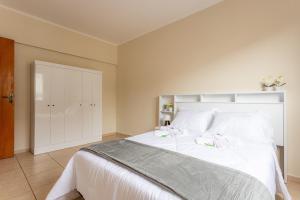 a bedroom with a large white bed with white pillows at Espaçoso com 2 Quartos, bem tranquilo c/ varanda! in Poços de Caldas +3 photos