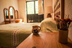 a vase sitting on a table next to a bed at Casa Aply in San Andrés Huayapan