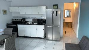 a kitchen with a stainless steel refrigerator and white cabinets at Playa Apartments in Salinas