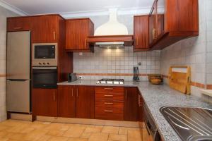 a kitchen with wooden cabinets and stainless steel appliances at Casa da Barragem da Vigia in Redondo