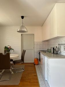 a kitchen with white cabinets and a table with chairs at Apartman Siesta in Kiseljak