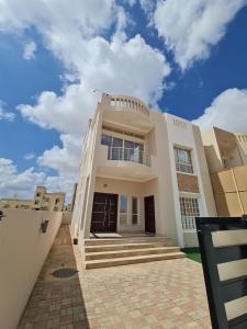 une grande maison blanche avec un ciel bleu dans l'établissement Villa Modern صلاله صحنوت, à Arzat 18 autres photos