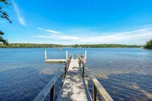 a dock on a lake with a boat in the water at Luxury Waterfront Home w Heated Pool and Hot Tub in Yarmouth