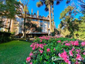 a large building with pink flowers in front of it at Apartamento 1 dormitório a 150m do Mini Mundo in Gramado