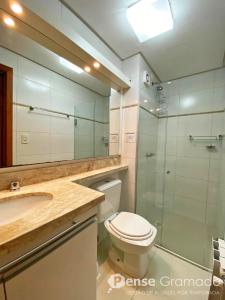 a bathroom with a toilet and a glass shower at Apartamento 1 dormitório a 150m do Mini Mundo in Gramado