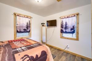 a bedroom with a bed and two windows at Resort Cabin on the River about 21 Mi to Crater Lake! in Chiloquin