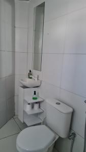 a white bathroom with a toilet and a sink at Apartamento central in Natal